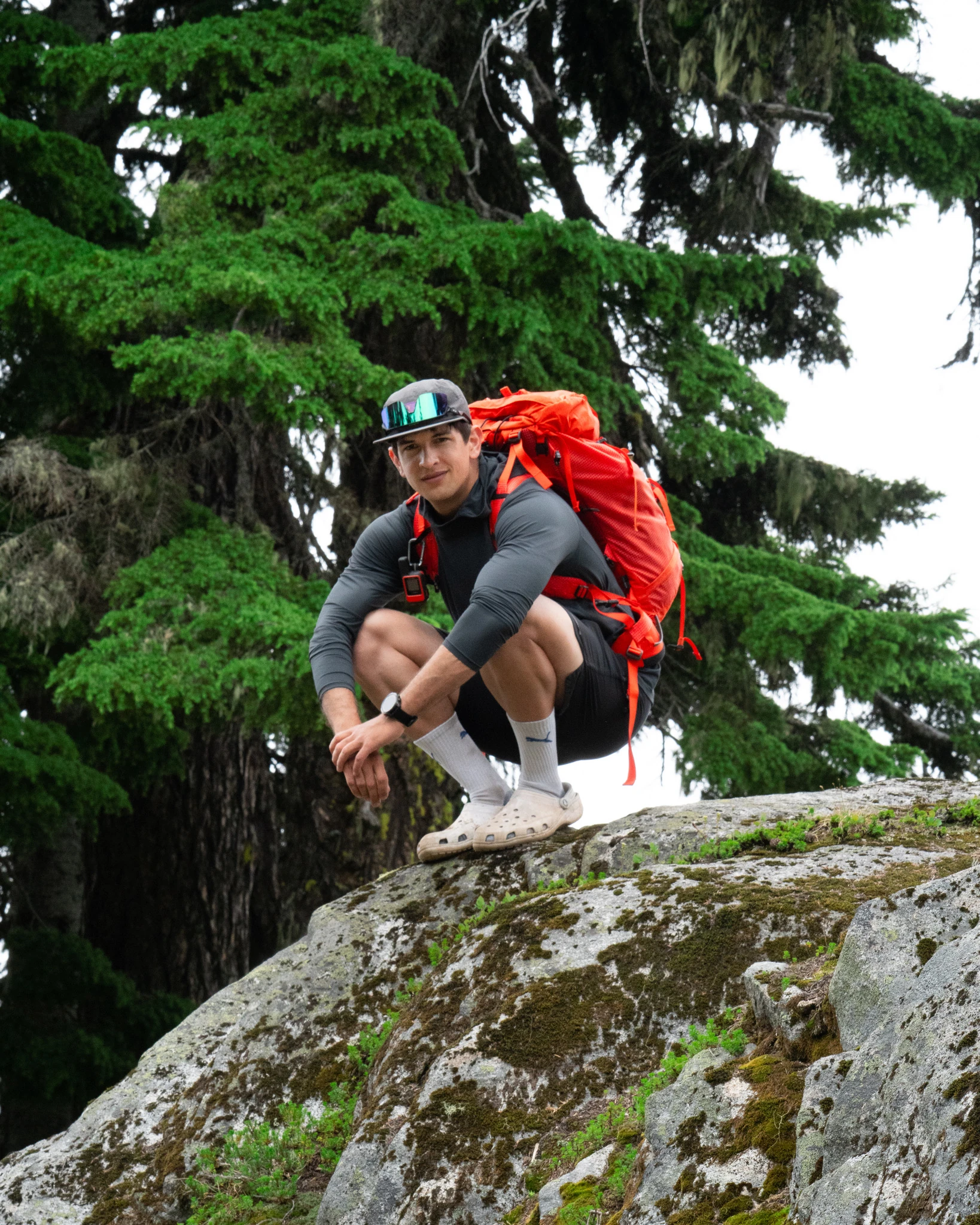 Max Patwardhan crouching on a rock with a red backpack